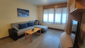 Una sala de estar con sofá, mesa de centro y televisor.