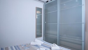 Une chambre à coucher avec un lit, un grand miroir et un placard à portes coulissantes en verre.