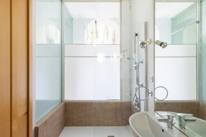 Een douche, een bidet, handdoeken, toiletpapier