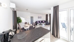 A modern living room with a dining area, a grey sofa, and a large window with curtains. - 2 bedroom awesome apartment in Okrug Gornji (Okrug Gornji)
