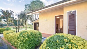 Un edificio con facciata beige, una porta con finestra e un piccolo portico.