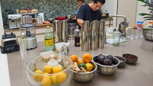A kitchen with various cooking appliances, a countertop with fruits and condiments, and a person preparing food. - El Pueblo Mérida (Mérida)