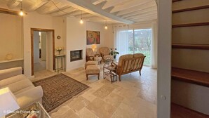 Ein großzügiges Wohnzimmer mit Kamin, bequemen Sitzgelegenheiten und einem großen Fenster mit Blick ins Freie.
