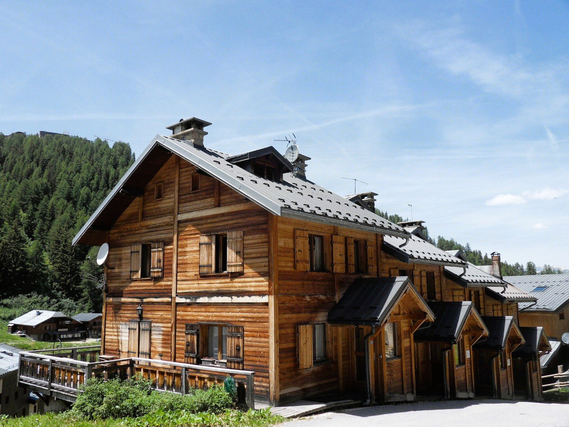 A wooden lodge with a sloped roof, multiple windows, and a satellite dish.