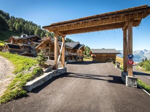 Eine Holzhütte mit überdachter Eingangspforte, einem Schild mit der Aufschrift 'Le Cocoon' und einem Parkschild, das einen privaten Parkbereich kennzeichnet.