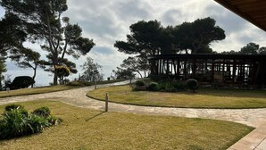 A pathway leading to a gazebo-like structure surrounded by trees and a body of water. - Apartment 'Eden Mar Calonge Girona' with Sea View, Shared Pool and Air Conditioning (Calonge)