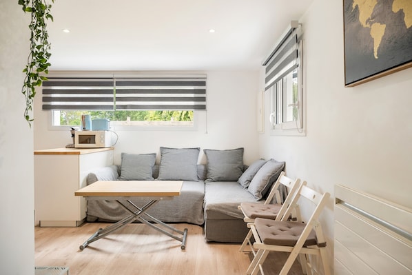 A compact living space with a sofa, a small table, and a radiator.