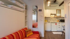 A compact living space with a sofa, a kitchen area, and a mirrored closet. - Studio Apartment "Casa Loredana" with Private Terrace & Wi-Fi (Venezia)