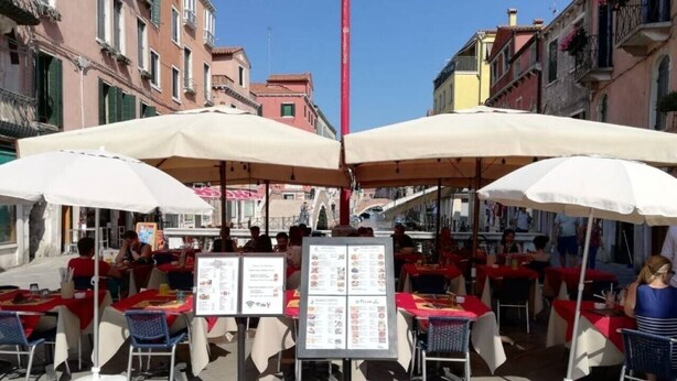 An outdoor café with tables and chairs, menus, and a clear sky. - Studio Apartment "Casa Loredana" with Private Terrace & Wi-Fi (Venezia)