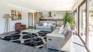 A modern living room with a sofa, armchair, coffee table, and a large window with a view.