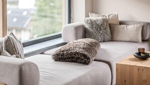 Ein modernes Wohnzimmer mit einem grauen Sofa, einem flauschigen Zierkissen und einem Holztisch mit einer Schale.