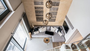 Ein modernes Wohnzimmer mit einem grauen Ecksofa, einem runden Couchtisch und einem großen Fenster.