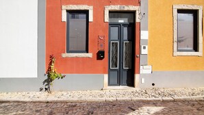 A building with a red and yellow facade, a black door, and a small window. - Villa 'Bougainvillea House' with Balcony, Wi-Fi and Air Conditioning (Faro)