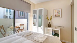 A hotel room with a bed, a desk, a chair, a wardrobe, and a window. - Villa 'Bougainvillea House' with Balcony, Wi-Fi and Air Conditioning (Faro)