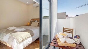 A bedroom with a bed, bedside table, and a view through a glass door. - Villa 'Bougainvillea House' with Balcony, Wi-Fi and Air Conditioning (Faro)