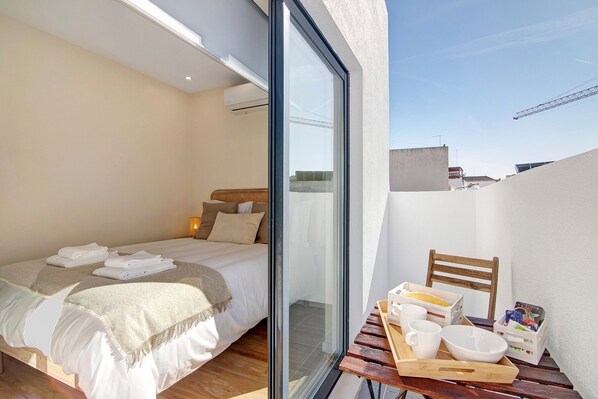 A bedroom with a bed, bedside table, and a view through a glass door.