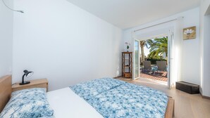 A bedroom with a bed, a nightstand, a desk lamp, a window, and a view of an outdoor patio area. - Villa 'Amarador' with Private Pool, Wi-Fi and Air Conditioning (Santanyí)