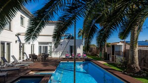A swimming pool with lounge chairs, a patio area, and a white building with a balcony. - Villa 'Amarador' with Private Pool, Wi-Fi and Air Conditioning (Santanyí)