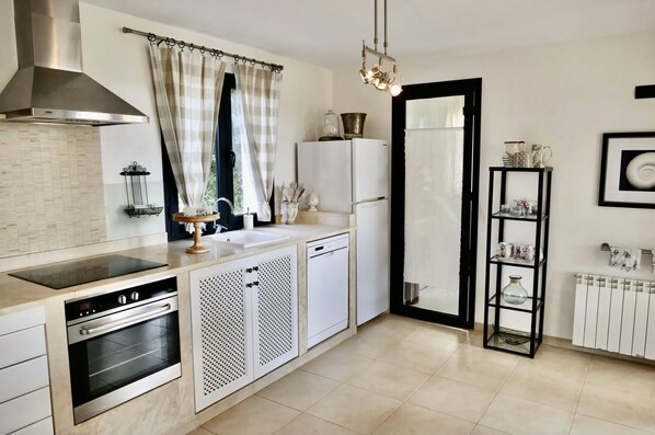 A modern kitchen with a stainless steel oven, a dishwasher, a white refrigerator, and a black shelf unit. - Vacation Home "Ocean Blues" with Private Pool, Shared Terrace & Wi-Fi (Cala Santanyí)