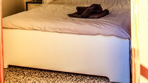 Une chambre à coucher avec un lit sous un dais, une table de chevet avec une lampe et un élément décoratif fixé au mur.