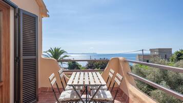Un balcón con una mesa y sillas, con vistas a la costa.
