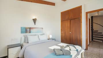 Un dormitorio con cama, mesita de noche, cuadro en la pared y un armario de madera.