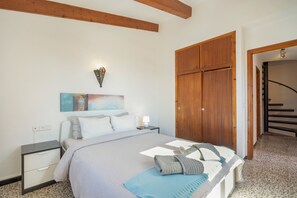 Une chambre à coucher comprenant un lit, une table de chevet, une commode, des œuvres d’art mural et une armoire en bois.