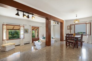 Amplia habitación con comedor, sofá y ventana con vistas a zonas verdes.