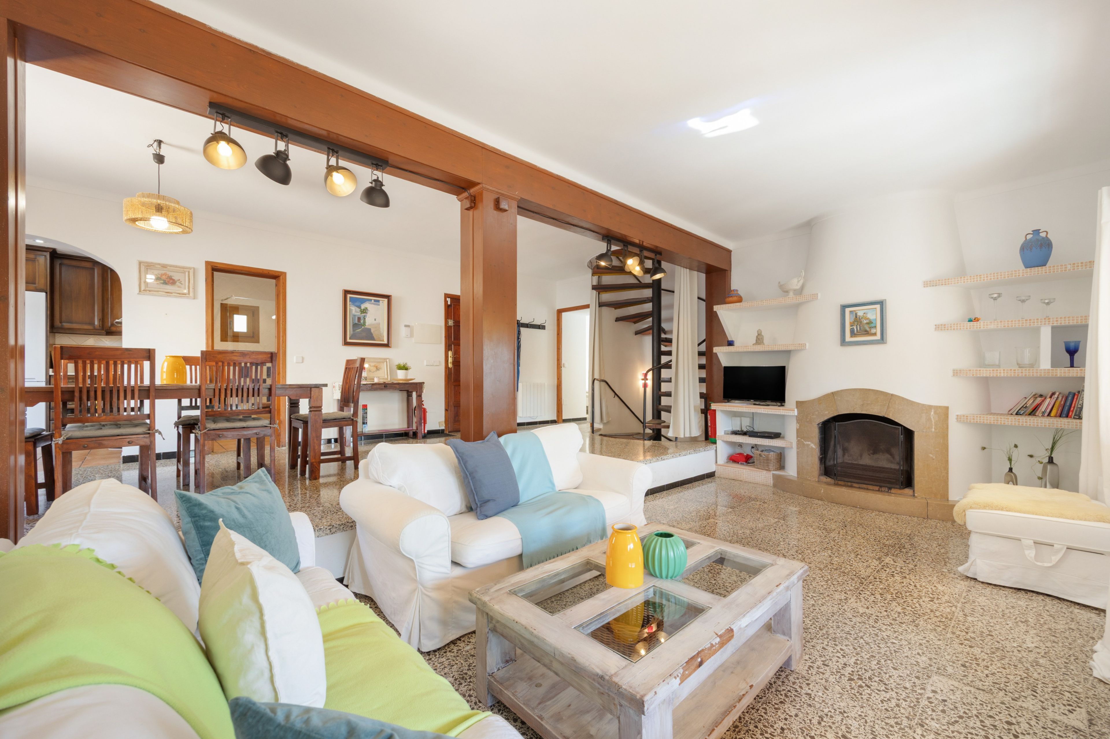 Una sala de estar con chimenea, un comedor y una escalera que sube a un nivel superior.