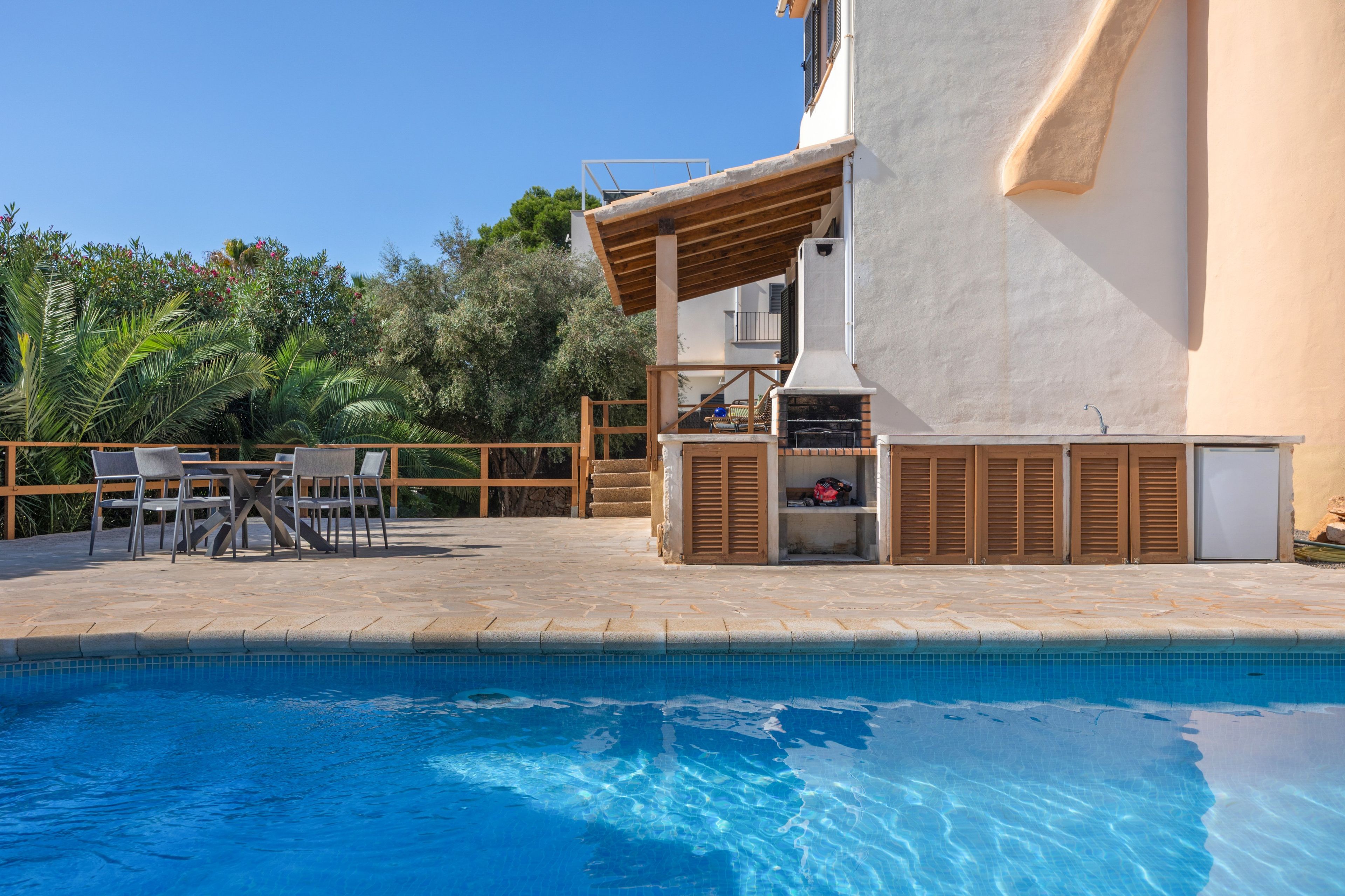 Ein Poolbereich mit Grill, Sitzmöglichkeiten im Freien und Blick auf den Pool.