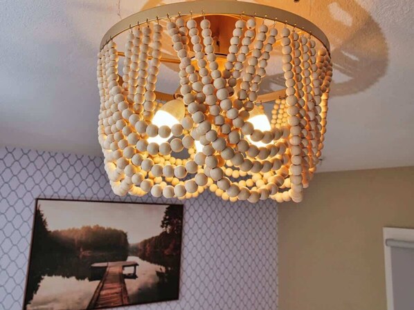 A ceiling with a decorative light fixture made of multiple layers of spherical beads.