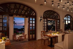 Dine with a view of the ocean from this elegantly furnished dining area with high ceilings and arched windows.