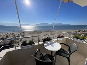Ein Balkon mit Tisch und Stühlen mit Blick auf einen Strand.