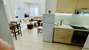 Una cucina compatta con frigorifero, fornello e lavandino. C'è un'area pranzo con divano e sedie.