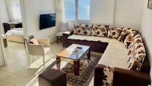 Un soggiorno moderno con un divano, poltrone, un tavolino da caffè e una televisione.
