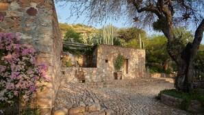 A stone building with a cobblestone path leading to it, surrounded by vegetation and trees. - Sagrada Holistic Ranch (San Miguel de Allende)