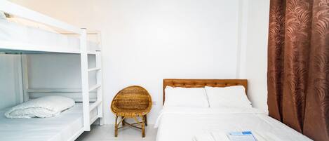 A room with a bunk bed, a single bed, a wicker chair, and a brown curtain.