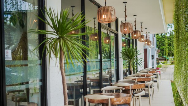 An outdoor cafe with tables and chairs, hanging lights, and potted plants. - Villa Soledad Garden Resort (San Pablo)