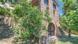 A stone building with an arched entrance, a bicycle, and greenery.
