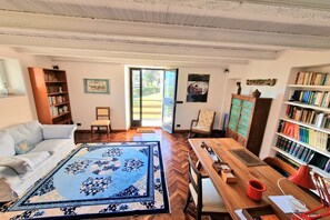 Une pièce comprenant un canapé, une table en bois, une bibliothèque et un tapis à motifs.