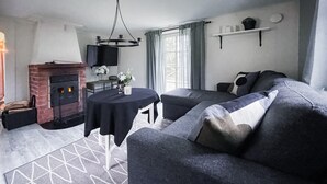 A modern living room with a fireplace, a round table, a sofa, and a patterned rug. - Amazing home in Kinnahult with WiFi (Kinnahult)