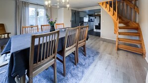 A dining area with a long table, wooden chairs, and a chandelier. A wooden staircase is visible to the right. - Amazing home in Kinnahult with WiFi (Kinnahult)