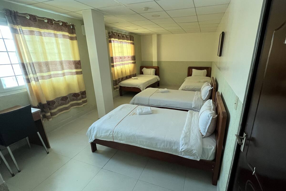A hotel room with two single beds, a desk, and a chair.