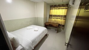 A small, clean room with a single bed, a wooden desk, and a window with curtains. - Residencial Cristina (Bocas del Toro)