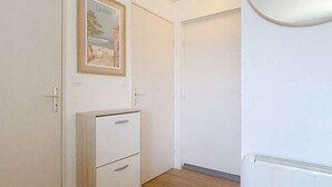 A hallway with wooden flooring, white walls, a framed picture, a white cabinet, and a radiator. - 01426 _ Apartment 4 people, residence with pool, Lacanau Ocean (LACANAU OCEAN)