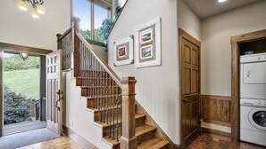 A staircase with wooden steps and metal railings, a door with a wooden frame, and a washing machine in a laundry room. - Tranquil Waters Retreat: Hot Tub, Pool & Lake Views (Smithville)