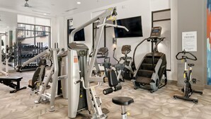 A modern gym with various exercise equipment, a large mirror, and a ceiling fan. - Arlington Spacious Studio Apartment (Arlington)