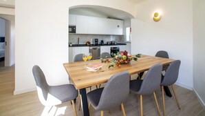 Un espace repas moderne avec une table en bois, des chaises à revêtement gris et un centre de table composé de fruits.
