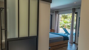 A bedroom with a bed, a view of the outdoors, and a sliding door.