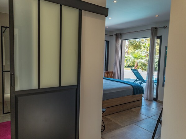 Een slaapkamer met een bed, uitzicht op het omliggende landschap en een schuifdeur.